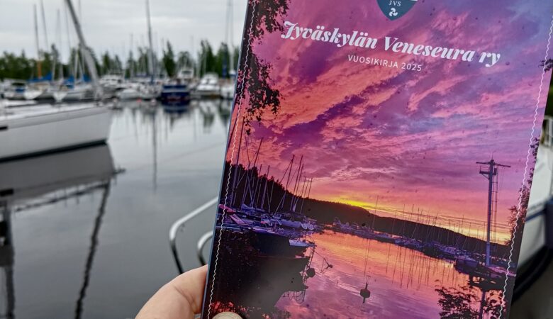 Kuvassa näkyy JVS:n vuosikirja taustanaan veneitä.